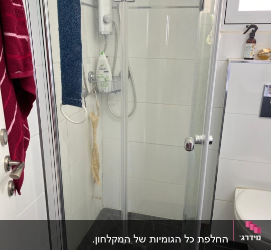 מקלחון זכוכית עם מגבת וסבון במקלחת